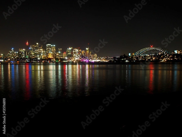 Fototapeta The lights of Sydney reflect in the harbor at night.