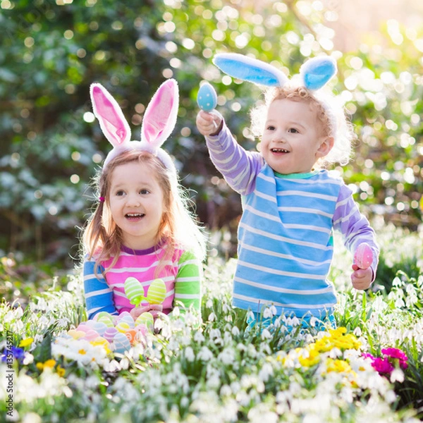 Fototapeta Kids on Easter egg hunt in blooming spring garden