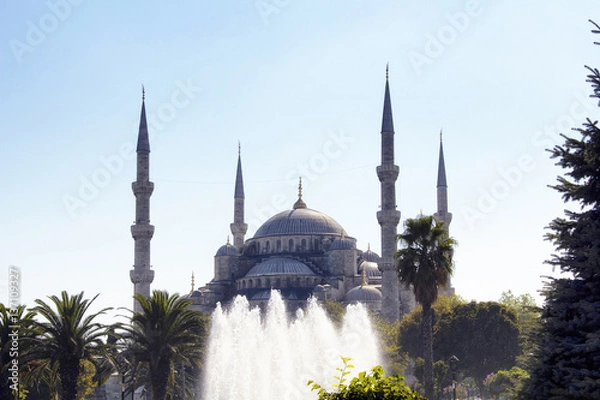 Fototapeta Distant view of Blue (Sultanahmet) Mosque with trees and water fountain in foreground. Well-known site built in 1616 & containing its founder's tomb.