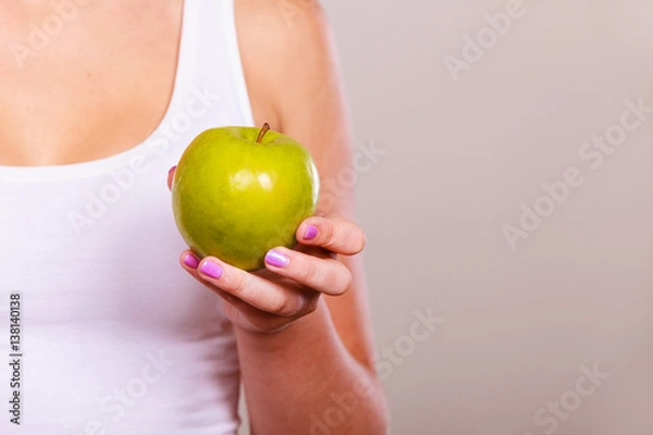 Fototapeta Fit woman holding apple fruit, dieting concept