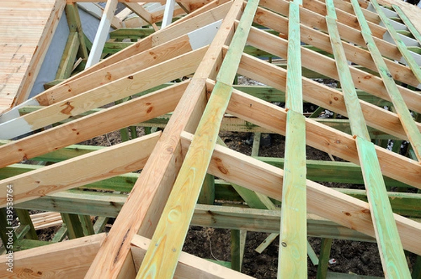 Fototapeta The wooden structure of the building. Wooden frame building. Wooden roof construction. Installation of wooden beams at construction the roof truss system of the house.