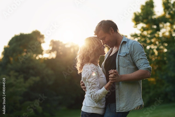 Fototapeta Romantic young couple dancing together outside at sunset