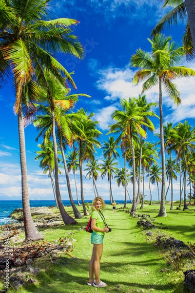 Fototapeta Young girl traveller on the green road with palm trees. Caribbean vacation. Samana, Dominican Republic