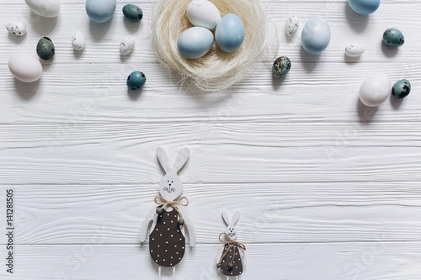 Fototapeta Blue and white Easter  eggs in nest on wooden background.