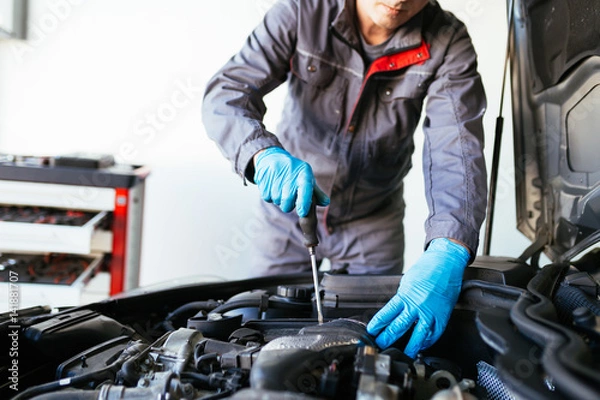 Fototapeta Auto mechanic repairing car. Selective focus on hands. 