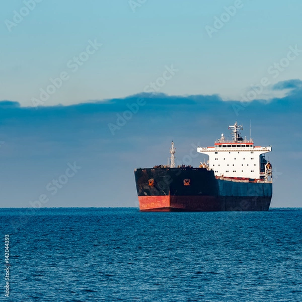 Obraz Black cargo ship moving in still Baltic sea water. Riga, Europe