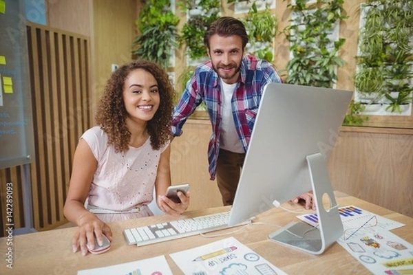 Fototapeta Portrait of business executives smiling at desk 