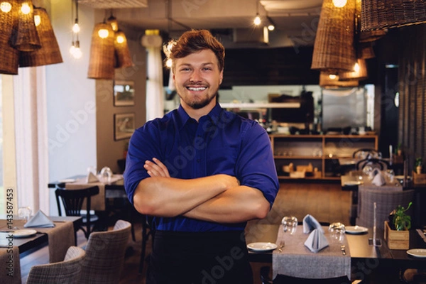 Fototapeta Cheerful waiter in modern restaurant