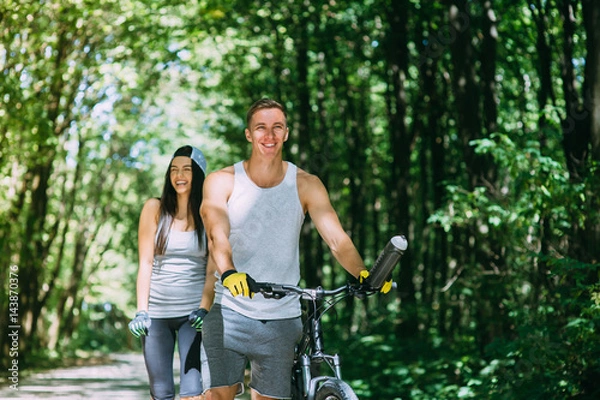 Fototapeta Young Couple Riding Bike In Park