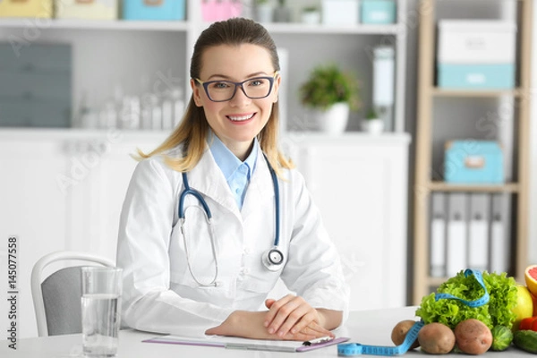 Fototapeta Young female nutritionist working in her office