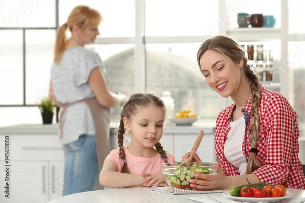 Fototapeta Young woman with her daughter in kitchen