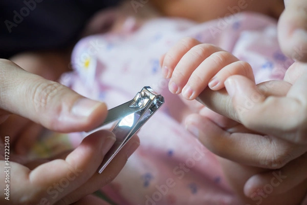 Fototapeta cutting,Mom tonsured nails on the hands newborn using nail scissors. Mother care is most important for baby healthy life,selective focus