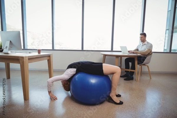 Fototapeta Executive exercising on fitness ball