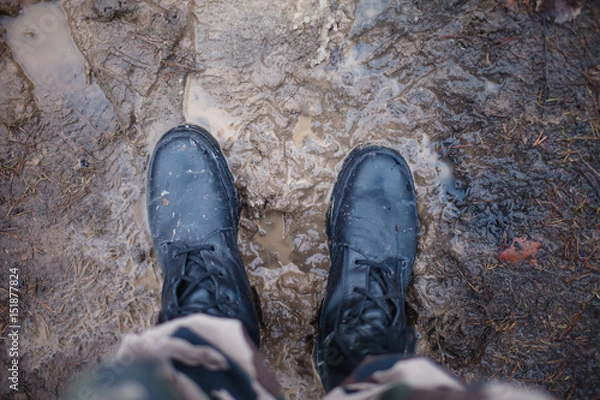 Obraz Army boots on dirty and damp earth at sunset