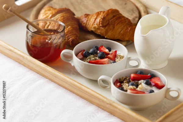 Fototapeta Tasty colorful Breakfast with Oatmeal, Yogurt, Strawberry, Blueberry, Honey and Milk on White Background. Breakfast in Bed. Copy Space. Top View.