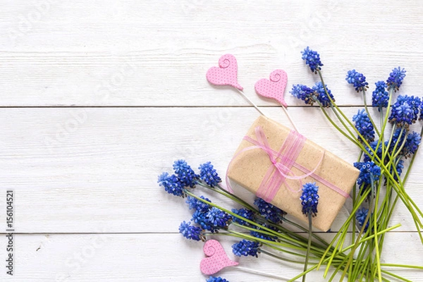 Fototapeta Gift box with blue muscari flowers and decorative hearts on white wooden background. Place for text.