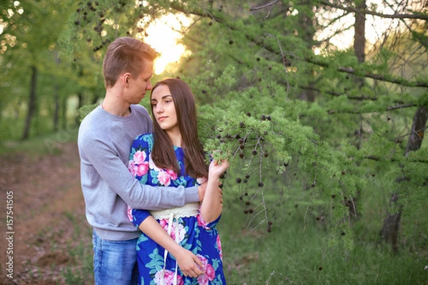 Fototapeta Loving guy and girl in a blooming apple orchard at sunset