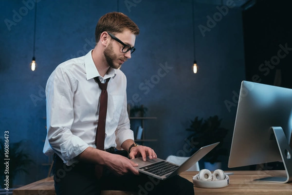 Fototapeta young businessman in formal wear working on laptop at modern office