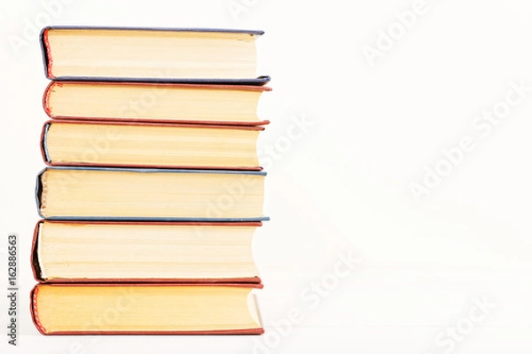 Fototapeta A stack of old books on a light beige background. Copyspace. Front view.