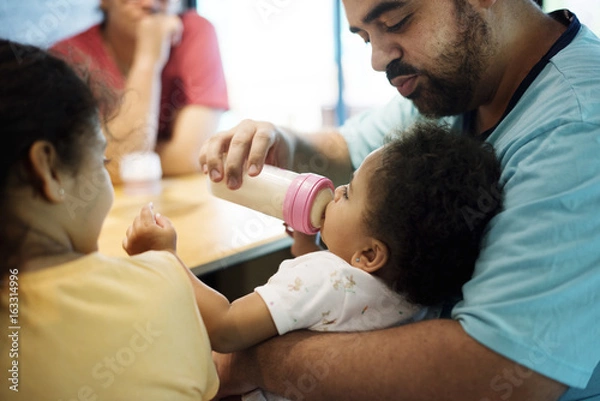 Fototapeta Closeup of brizilian father feeding toddler daughter