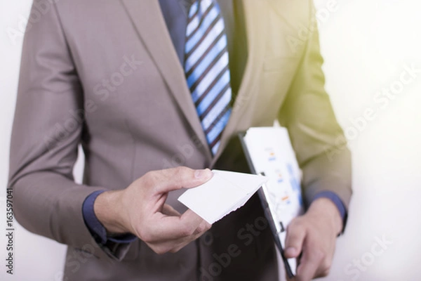 Fototapeta Close up view of a young businessman holding his business camera toward the camera white background. Copy space on the card. Close-up of a man giving a business card.