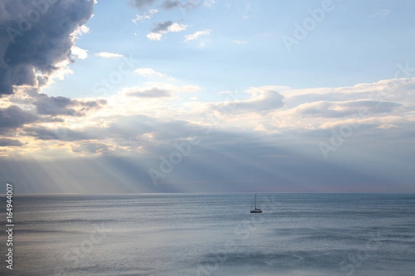 Fototapeta yacht in the sea rays from clouds landscape