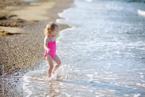 Fototapeta The cute little girl runs on the beach at the seashore