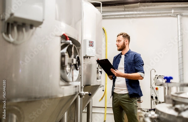 Fototapeta man with clipboard at craft brewery or beer plant