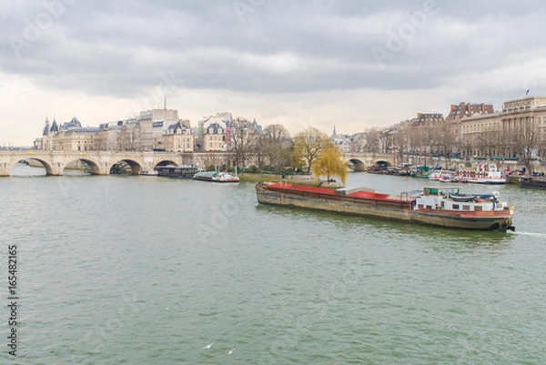 Fototapeta      Paris, view of the Seine from the pont des Arts, with the Pont-Neuf and a barge crossing 