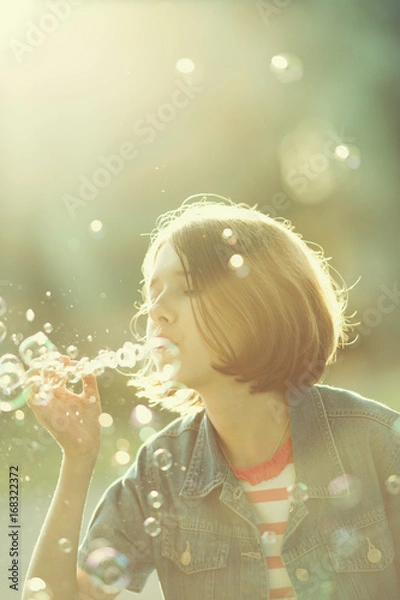 Fototapeta Portrait of teenager blowing soap bubbles