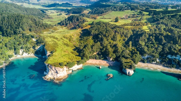 Fototapeta Aerial view on a small beach surrounded by rocks and forest. Coromandel, New Zealand