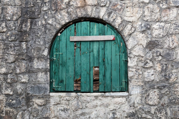 Fototapeta Ancient semicircular window with nailed green wooden shutters.