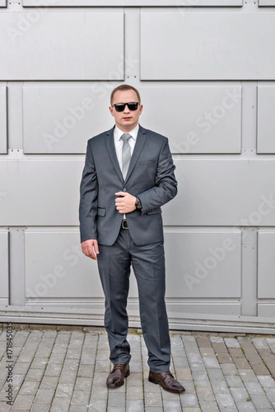 Fototapeta portrait of a young serious  smiling businessman in grey blue suit