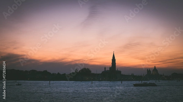 Fototapeta Italian silhouette of Venice at sunset with boats, Italian city panorama vintage shot from sea and sky, Sunset in Venice background, Dark scene of Venice skyline, Symbol of evening Venice