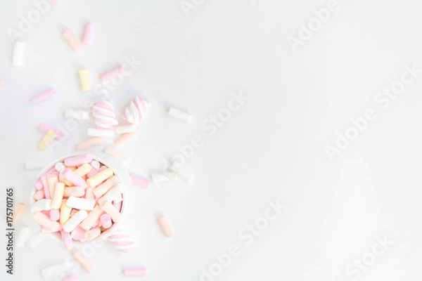 Fototapeta Colorful light marshmallows in a cup on white background. Top view, flat lay