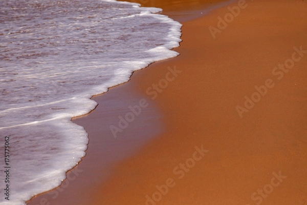 Fototapeta Wave of blue ocean on sandy beach. Background.