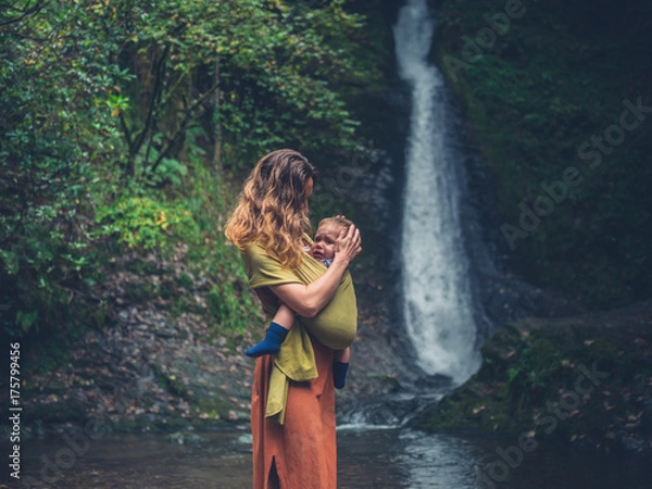 Fototapeta Mother with baby standing by waterfall