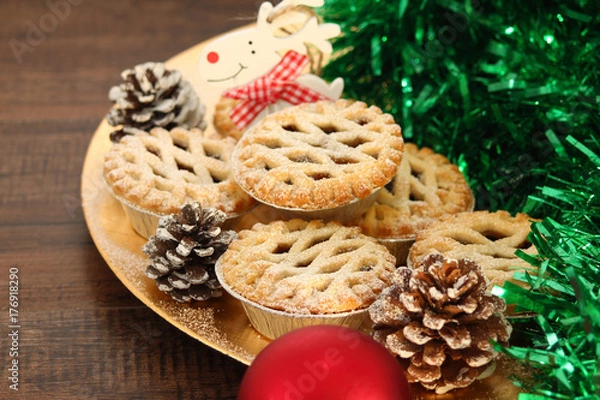 Fototapeta Christmas mince pies on a gold plate with red reindeer on a wood background
