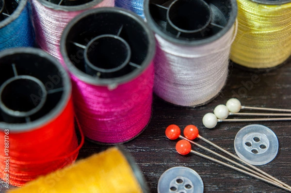 Fototapeta Sewing threads on a wooden background