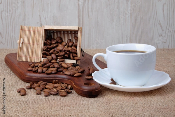 Fototapeta Cup of dark coffee with coffee beans on wooden cutting board . Relax time concept.