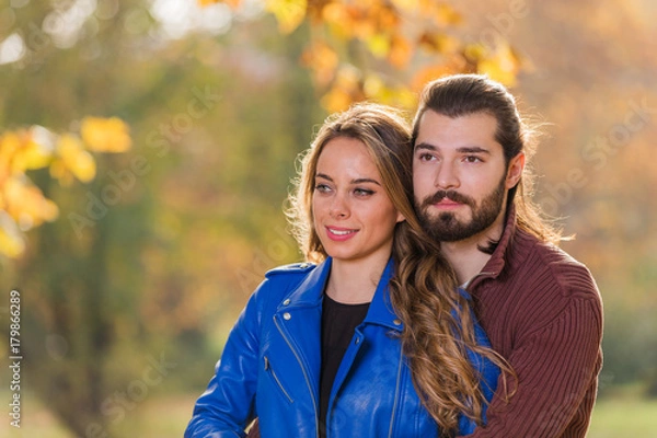 Fototapeta Cute couple in park filled with autumn colors.