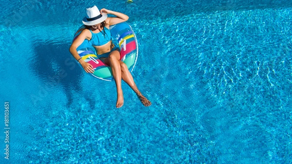 Fototapeta Aerial top view of beautiful girl in swimming pool from above, relax swim on inflatable ring donut and has fun in water on family vacation
