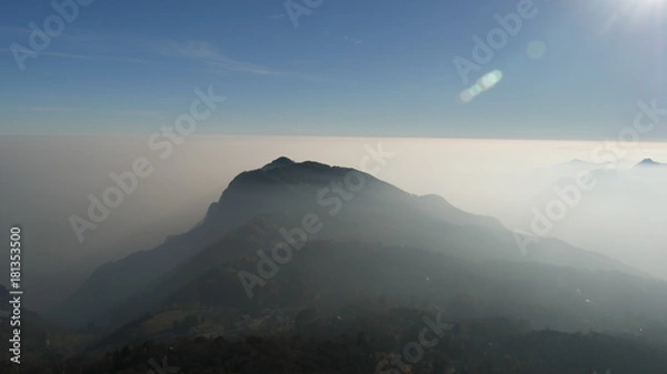 Fototapeta Nebbia in pianura e cielo azzurro sulle montagne