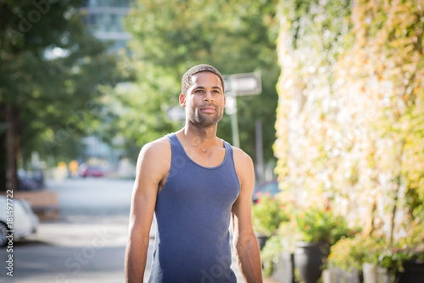 Fototapeta Street portrait of gentle and handsome African American man in unfriendly neighborhood on a bright sunny day