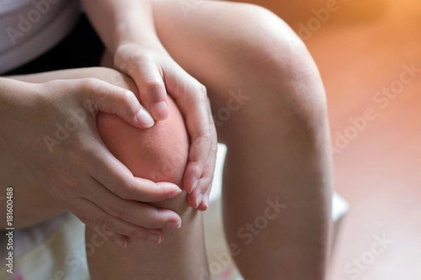 Fototapeta A young woman massaging her painful knee