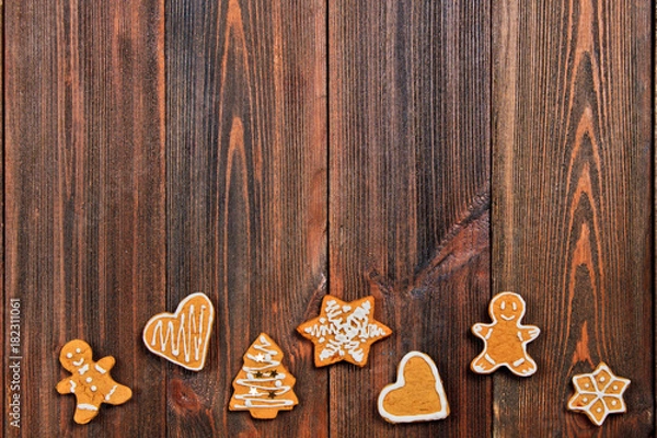 Fototapeta Christmas gingerbread cookies of different shapes on a brown wooden table. Copy space.