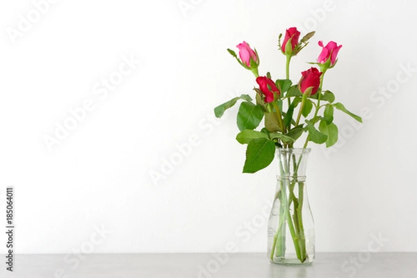 Fototapeta Red and pink roses in glass vase on table and white wall background with copy space, Happy valentine's day concept