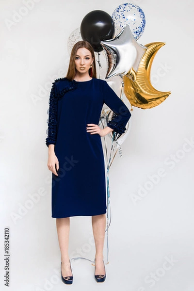 Fototapeta Joyful young woman in luxury dress on heels celebrating new year in studio. Having fun with balloons