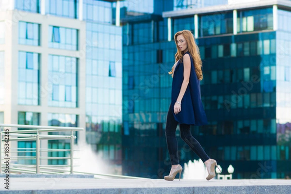 Fototapeta Happy woman standing outdoors in business casual suite against modern mall