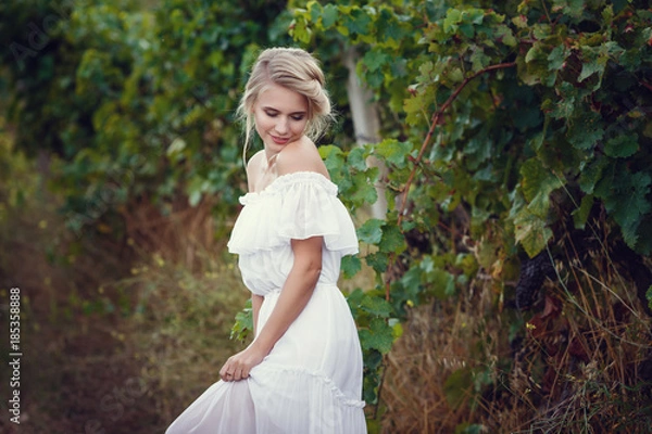 Fototapeta Beautiful blond girl with basket of grapes in a vineyard